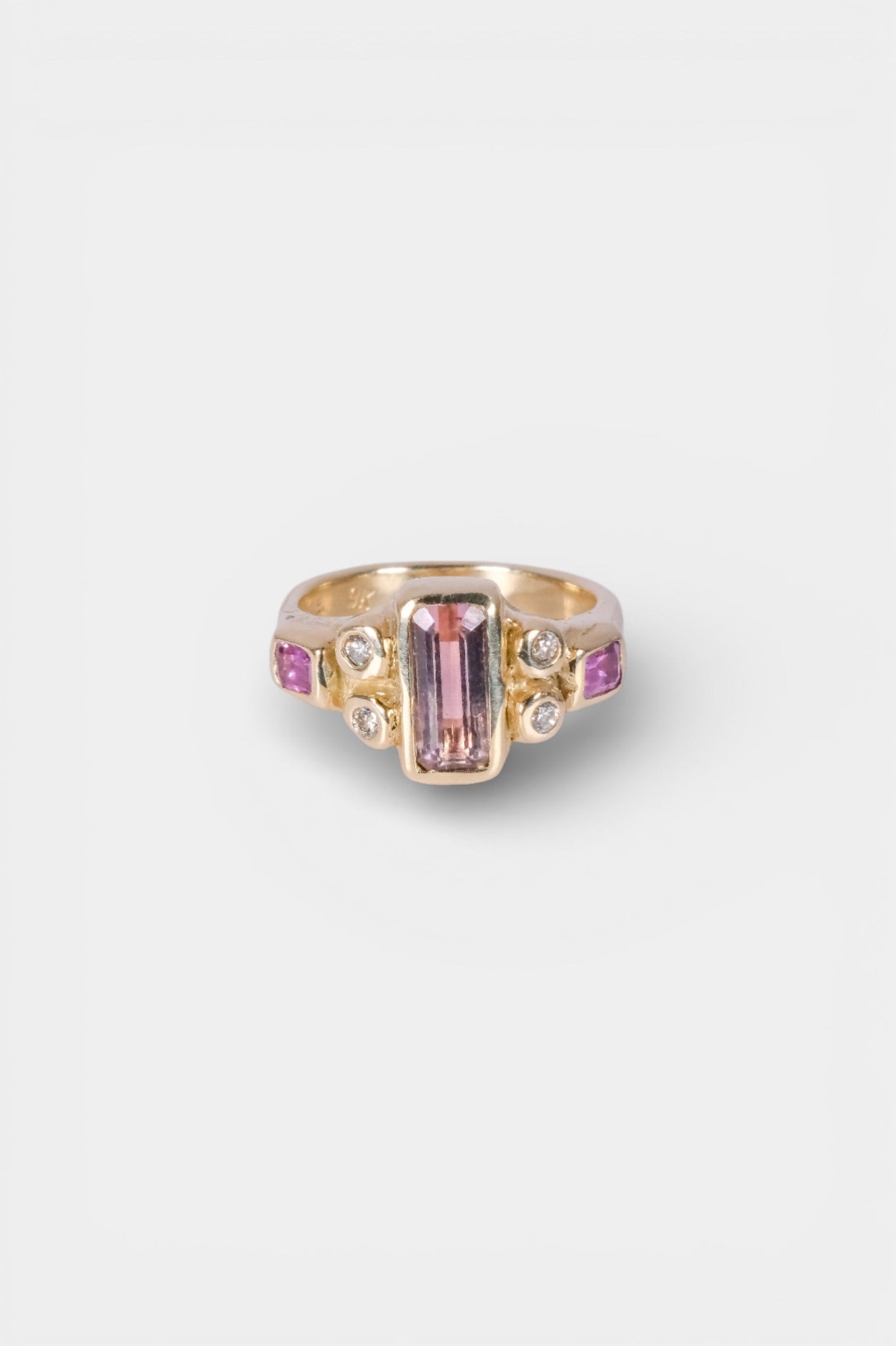 Gold ring with pink gemstone on a white background