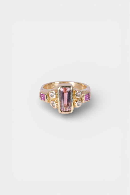 Gold ring with pink gemstone on a white background