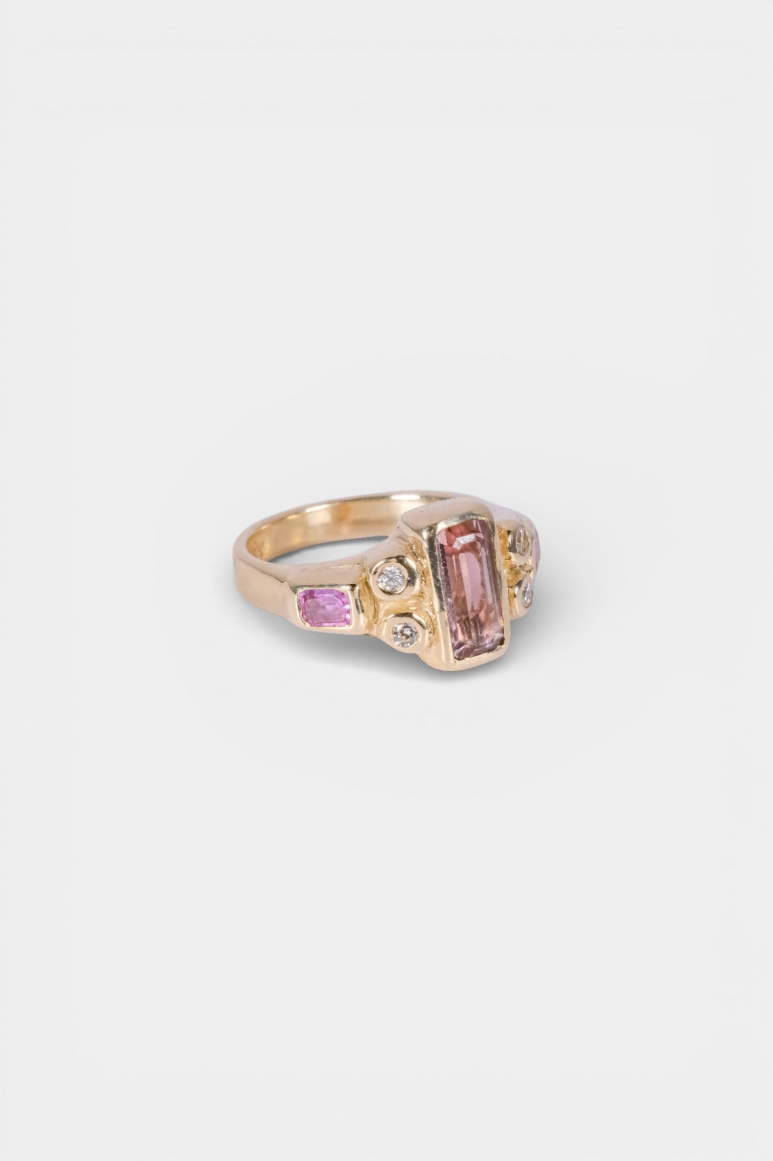 Gold ring with pink gemstone on a light gray background